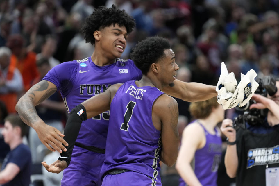 Furman guard JP Pegues (1) reacts with forward Tyrese Hughey after the team defeated Virginia in a first-round college basketball game in the NCAA Tournament Thursday, March 16, 2023, in Orlando, Fla. (AP Photo/Chris O'Meara)