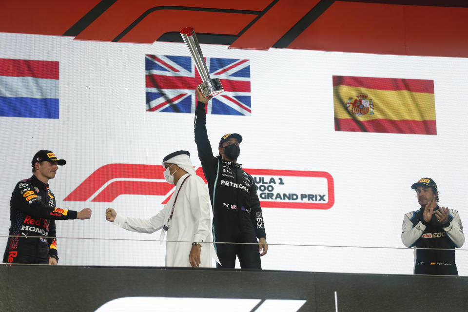 Mercedes driver Lewis Hamilton of Britain waves from the podium after winning the Qatar Formula One Grand Prix. In Lusail, Qatar, Sunday, Nov. 21, 2021. On the left is second placed Red Bull driver Max Verstappen of the Netherlands and on the right third placed Alpine driver Fernando Alonso of Spain. (Hamad I Mohammed, Pool via AP)
