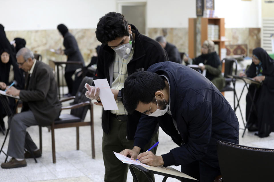 Voters with face masks fill out their ballots in the parliamentary elections at a polling station in Tehran, Iran, Friday, Feb. 21, 2020. Iranians began voting for a new parliament Friday, with turnout seen as a key measure of support for Iran's leadership as sanctions weigh on the economy and isolate the country diplomatically. Also looming over the election is the threat of the new coronavirus, which has been confirmed in five people in Iran this week, including two elderly citizens who died in the city of Qom. Concerns over the spread of the virus, which originated in central China, prompted authorities in Iran to close all schools and Shiite seminaries in Qom. (AP Photo/Vahid Salemi)