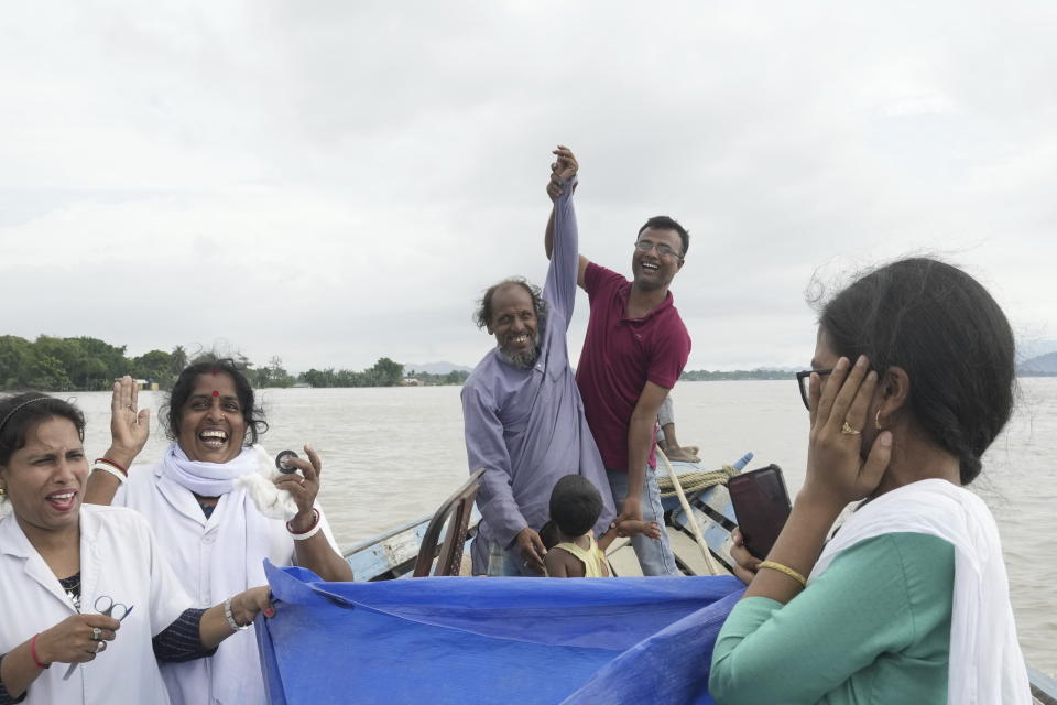 Un miembro del equipo médico alza la mano de Kamaluddin mientras celebran el nacimiento exitoso de su hija recién nacida en un barco camino de un centro médico, en el río Brahmaputra, en el estado norteño de Assam, India, el miércoles 3 de julio de 2024. (AP Foto/Anupam Nath)