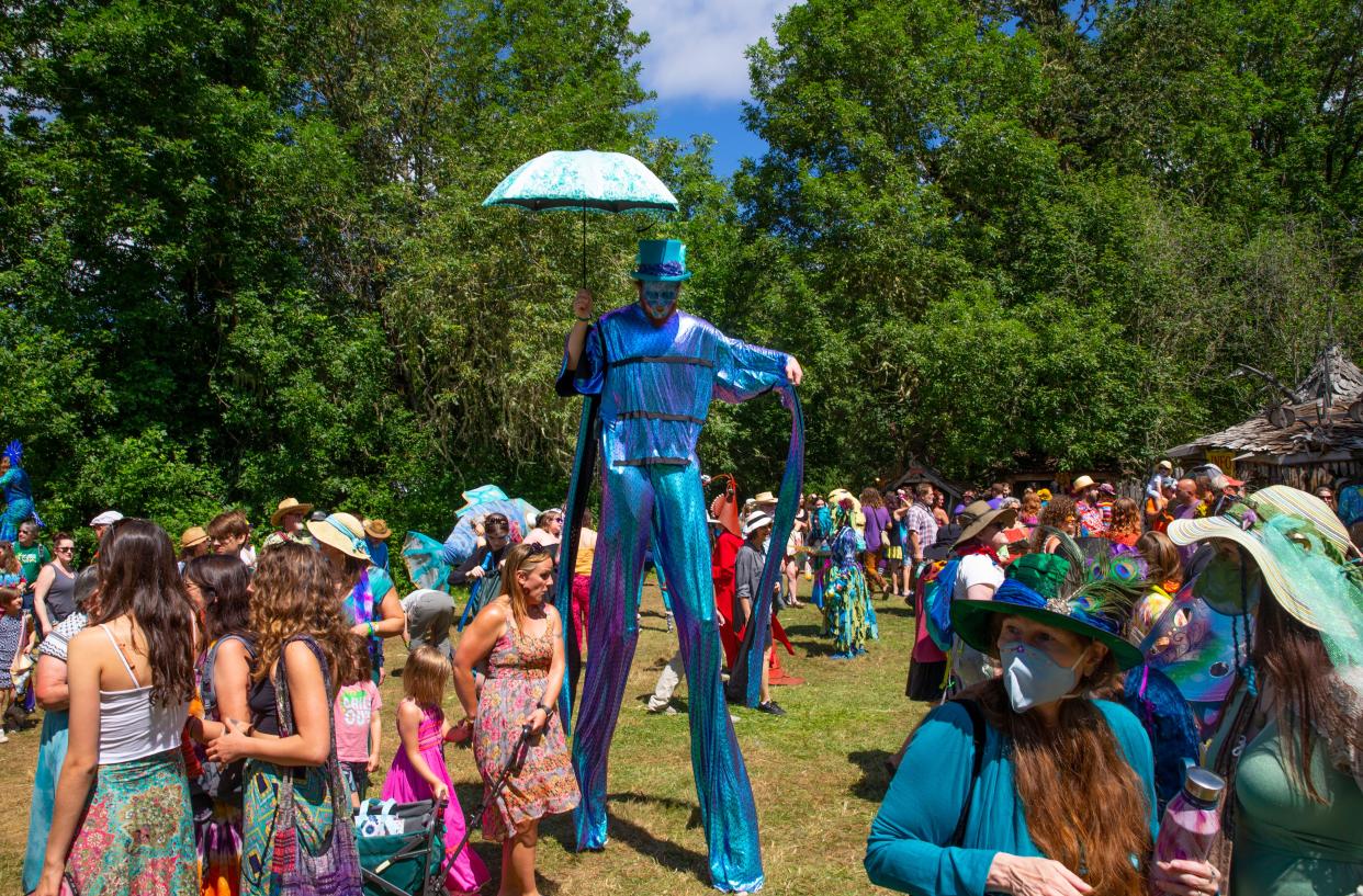 A stilt walker navigates the crowds on opening day of the Oregon Country Fair 2022.