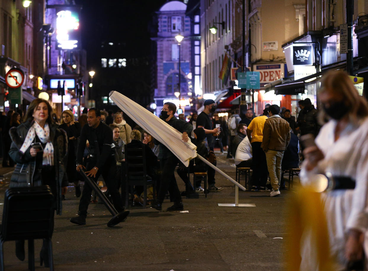 Bar staff begin clearing street furniture ahead of closing time in Soho, London, after pubs and restaurants were subject to a 10pm curfew to combat the rise in coronavirus cases in England.