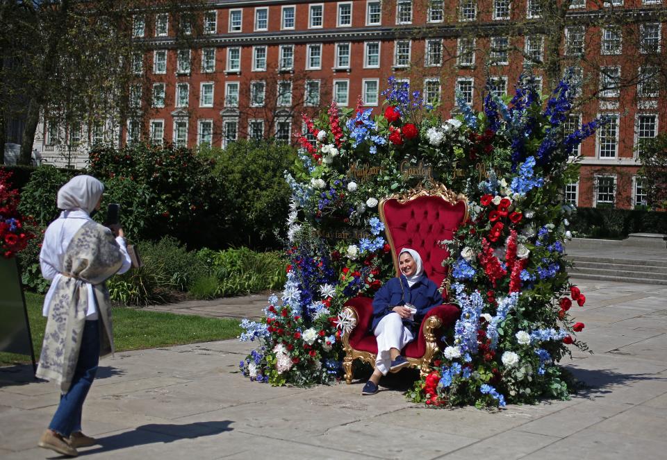 Members of the public take photos of themselves in a flower-adorned throne on Grosvenor Square in central London ahead of the coronation ceremony of Charles III and his wife, Camilla, as King and Queen of the United Kingdom and Commonwealth Realm nations, on May 6, 2023.