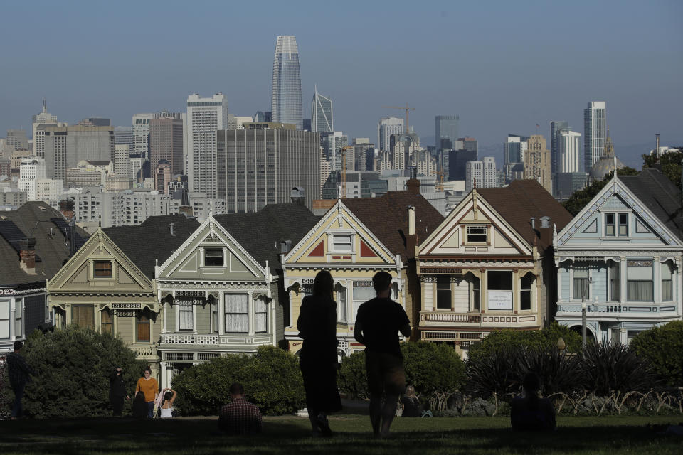 Visitors look toward the "Painted Ladies," a row of historical Victorian homes, in front of the San Francisco skyline from Alamo Square Park in San Francisco, Wednesday, Feb. 26, 2020. California officials are bracing for the potential of another drought and an early and more intense wildfire season amid a record-breaking warm and dry February. (AP Photo/Jeff Chiu)