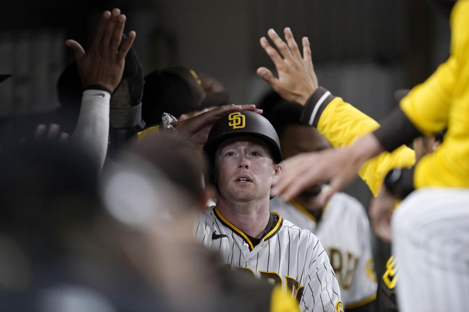 San Diego Padres' Jake Cronenworth is greeted in the dugout after scoring off an RBI-double by Manny Machado during the sixth inning of a baseball game against the Chicago Cubs, Tuesday, May 10, 2022, in San Diego. (AP Photo/Gregory Bull)