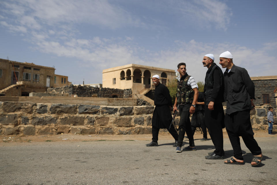 In this Thursday, Oct. 4, 2018, photo, Druze men walk in the village of Rami in the southern province of Sweida, Syria. Three months after a stunning Islamic State attack on a southeastern corner of Syria in which more than 200 people were killed and 30 women and children abducted, tensions are boiling over, and young men are taking up arms. It is a stark change for a province that managed to stay on the sidelines of the seven-year Syrian war and where most villagers worked grazing livestock over surrounding hills. (AP Photo/Hassan Ammar)