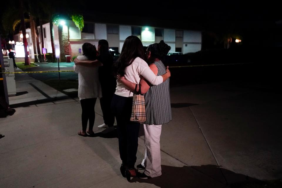 People are pictured comforting each other as they stand near a business building where a shooting occurred in Orange, California. Authorities say 4 people, including a child, died during the shooting late Wednesday.