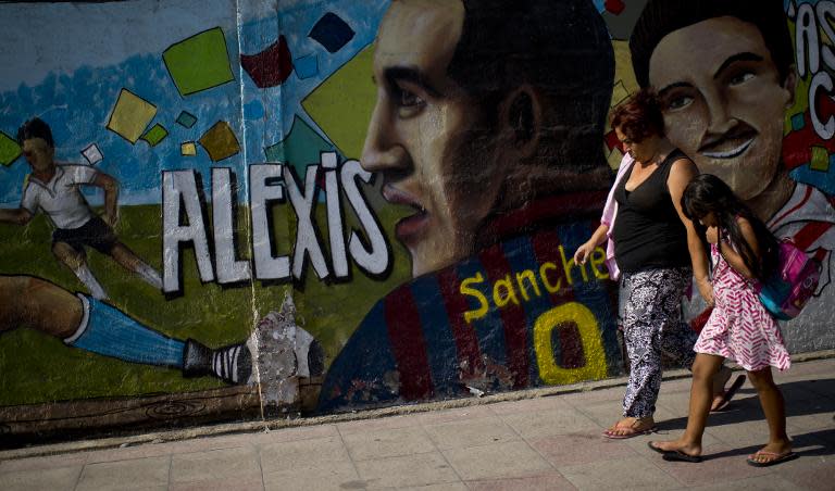 A woman walks by a wall with an image of Chilean footballer Alexis Sanchez in Tocopilla port, on February 17, 2015