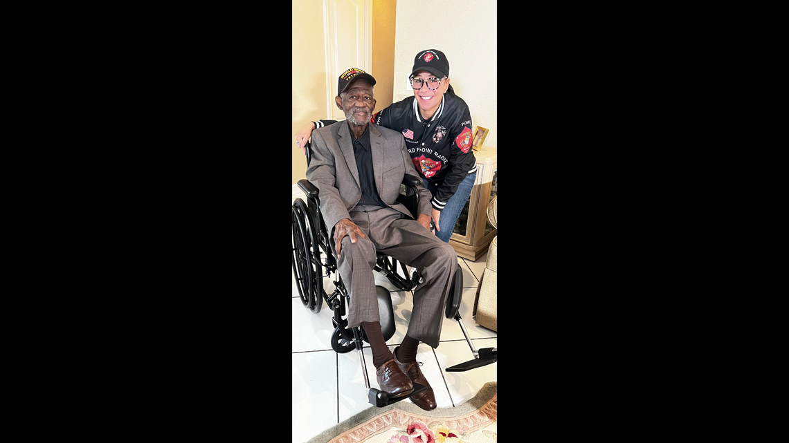 George Johnson, a former Marine Corps corporal and World War II veteran, sits with Mallorie Berger, an advocate for members of of his training unit, the Montford Point Marines. They were the first Black Marines allowed in the service in World War II.