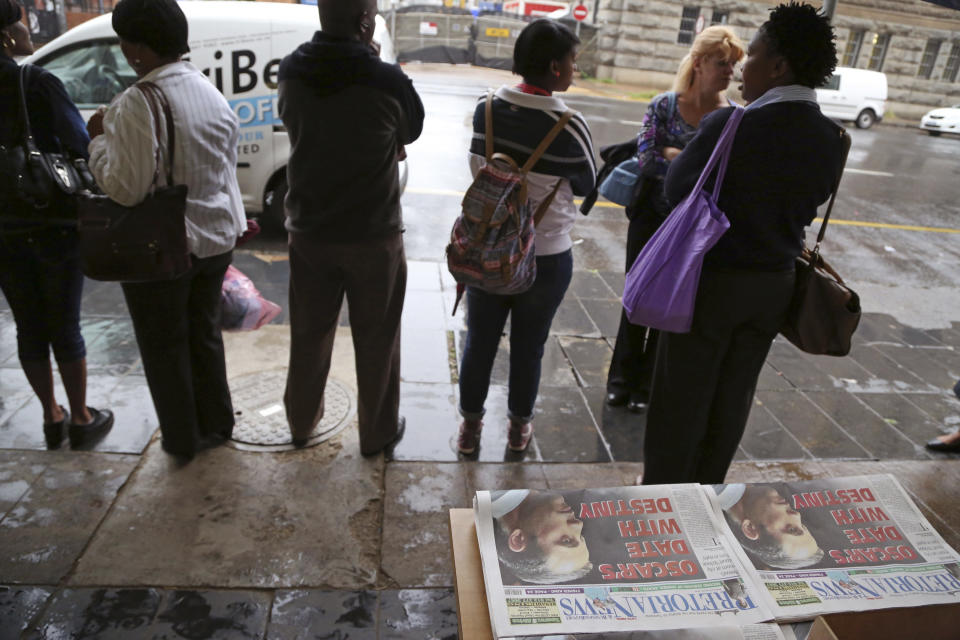 People stand around a newspaper reading "Oscar's date with destiny" before Oscar Pistorius arrives at the high court in Pretoria, South Africa, Monday, March 3, 2014. Pistorius is charged with premeditated murder for the shooting death of his girlfriend, Reeva Steenkamp, on Valentine's Day in 2013. (AP Photo/Schalk van Zuydam)
