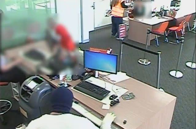 A man with long light brown hair confronted a woman at the teller before approaching a worker, while his accomplice searched behind the teller. Source: Victoria Police