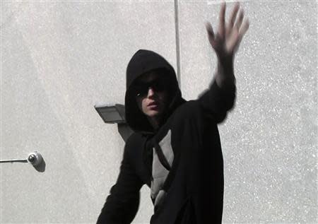 Pop singer Justin Bieber waves to fans as he leaves a jail after being released on bail in Miami, Florida in this still image taken from video January 23, 2014. REUTERS/Reuters TV