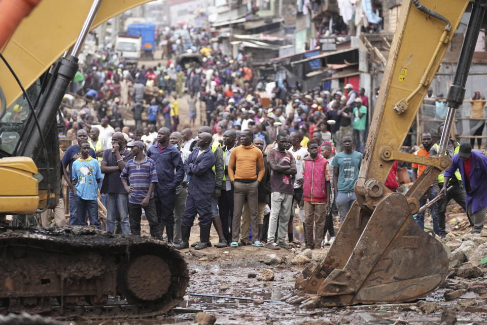 Residents watch as excavators and bulldozers bring down their homes in the Mathare area of Nairobi, Kenya Wednesday, May. 8, 2024. The Kenyan government ordered the evacuation of people from flood-prone areas, resulting in the demolition of houses and the loss of at least one life in the melee caused by the forced evictions. (AP Photo/Brian Inganga)