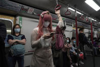 A woman wearing a face mask as a precaution against the COVID-19 while using smartphone in a subway train in Hong Kong, Thursday, Feb. 27, 2020. As the worst-hit areas of Asia continued to struggle with a viral epidemic, with hundreds more cases reported Thursday in South Korea and China, worries about infection and containment spread across the globe. (AP Photo/Kin Cheung)