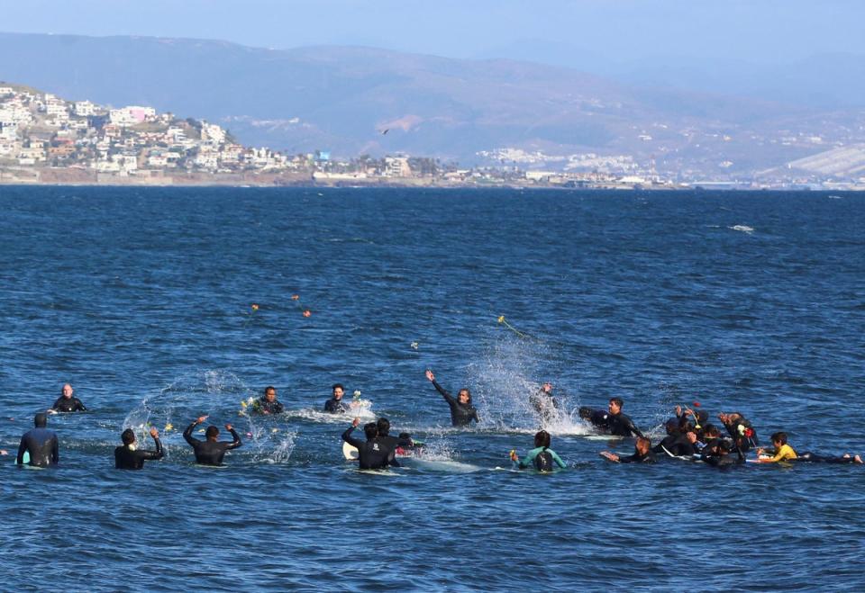 Local surfers throw flowers during a demonstration calling for authorities to solve the killings in Ensenada (REUTERS)