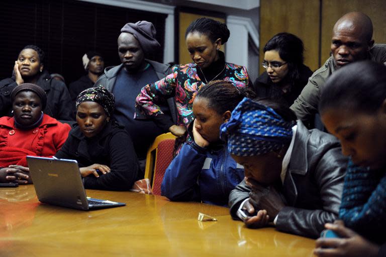 Relatives of miners killed during the Marikana police shooting in 2012 listen on a device to South African President Jacob Zuma delivering the findings of a commission of inquiry, on June 25, 2015 at the Marikana settlement near Rustenburg