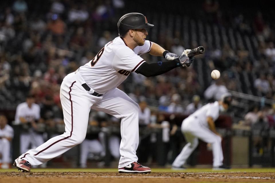 Arizona Diamondbacks' Merrill Kelly drops down a sacrifice bunt against the Miami Marlins during the fifth inning of a baseball game Thursday, May 13, 2021, in Phoenix. (AP Photo/Ross D. Franklin)