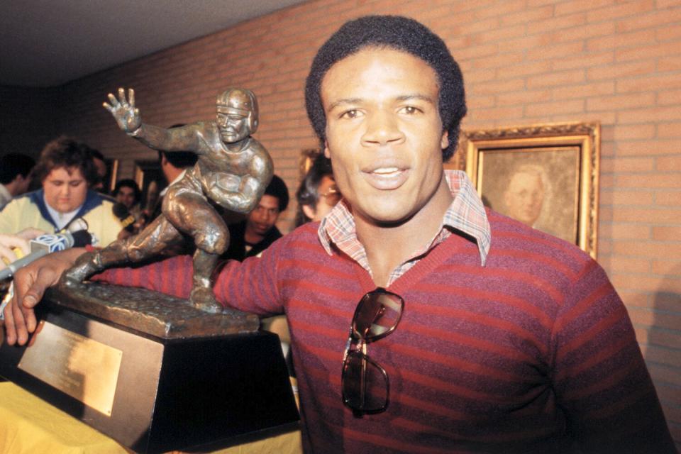 USC's Charles White, winner of the 1979 Heisman Trophy, puts his arm around the same trophy won by O.J. Simpson during press conference