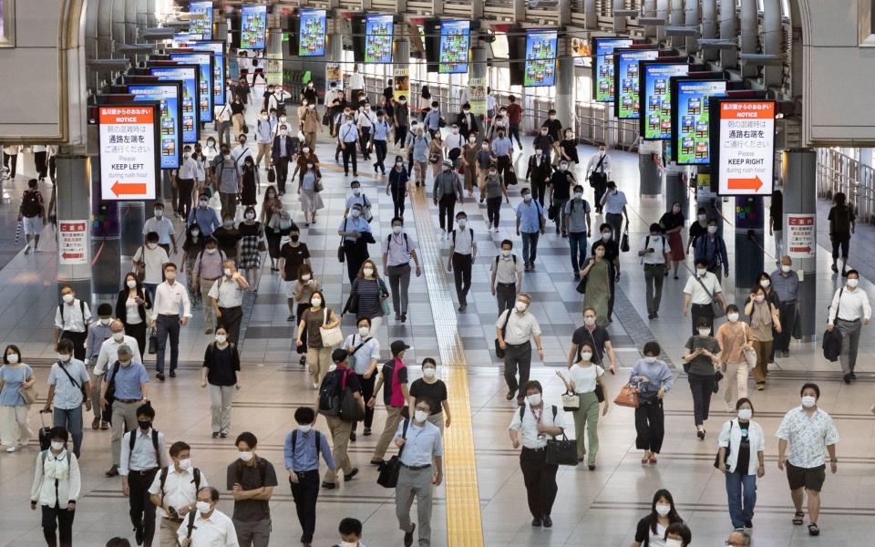 Commuters wear masks at a train station in Tokyo - YUKI IWAMURA/AFP