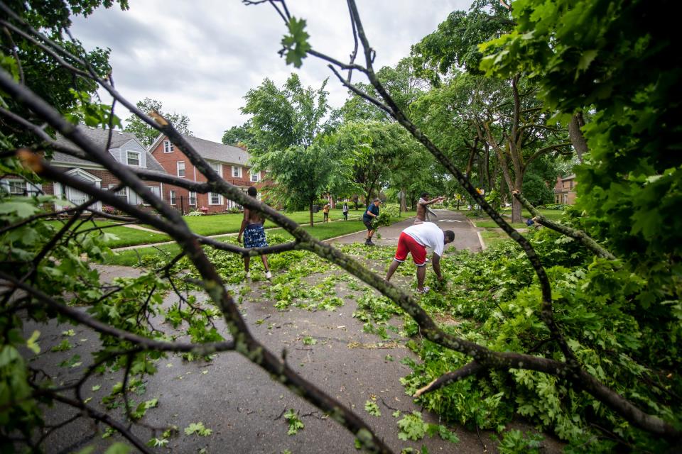 Right to left, DeAryus Williams, 19, Cam, 17, Lorenzo Blount, 66, and Tre Amando, 18, clear the road after a flash storm around the Grandmont neighborhood in Detroit on Wednesday, June 1, 2022. 