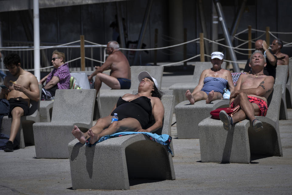 People sunbathe near the beach in Barcelona, Spain, Tuesday, June 8, 2021. Spain is jumpstarting its summer tourism season by welcoming vaccinated visitors from most countries as well as European visitors who can prove they are not infected with coronavirus. (AP Photo/Emilio Morenatti)