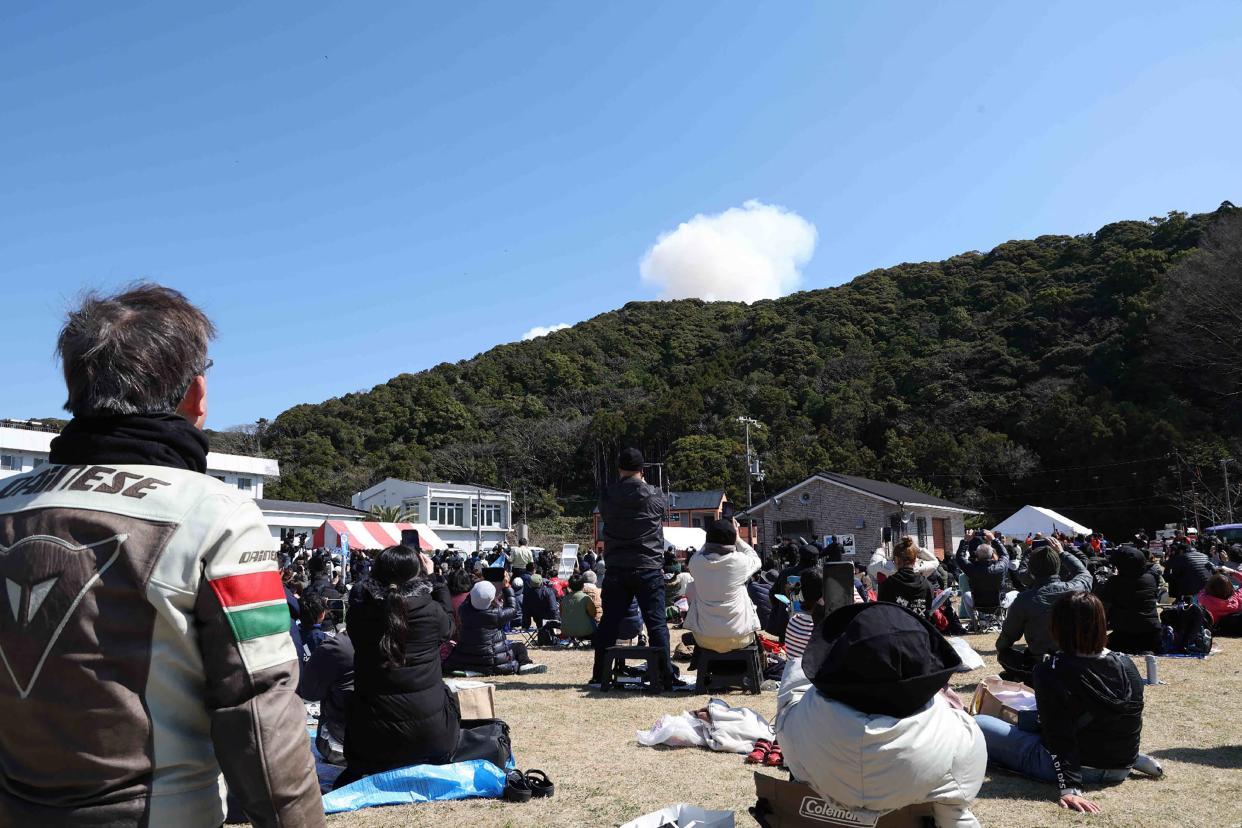 Visitors look on Wednesday as smoke rises from behind a hill after a small rocket by Tokyo-based startup Space One exploded upon take-off, at the Spaceport Kili site in Kushimoto, Wakayama prefecture. The rocket made by a Japanese startup exploded just after launch when the company aborted its attempt to become the nation's first private firm to put a satellite into orbit.