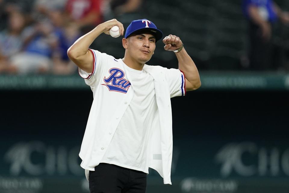 Boxer Vergil Ortiz Jr., flexes as fans appaud before throwing out the ceremonial first pitch before a baseball game between the Cleveland Guardians and Texas Rangers in Arlington, Texas, Saturday, Sept. 24, 2022. (AP Photo/Tony Gutierrez)