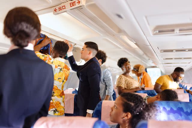 <p>Getty</p> Stock image of people standing in the aisle and sitting in their seats on an airplane.