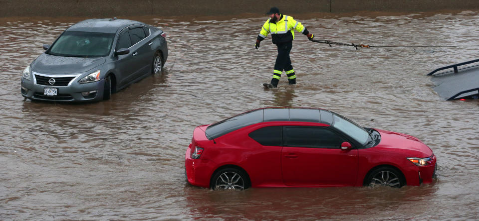 A tow truck driver moves to clear a flooded car as another rolls along Interstate 70 at Mid Rivers Mall Drive in St. Peters after heavy rain fell through Monday night and into the morning on Tuesday, July 26, 2022. (Robert Cohen/St. Louis Post-Dispatch via AP)