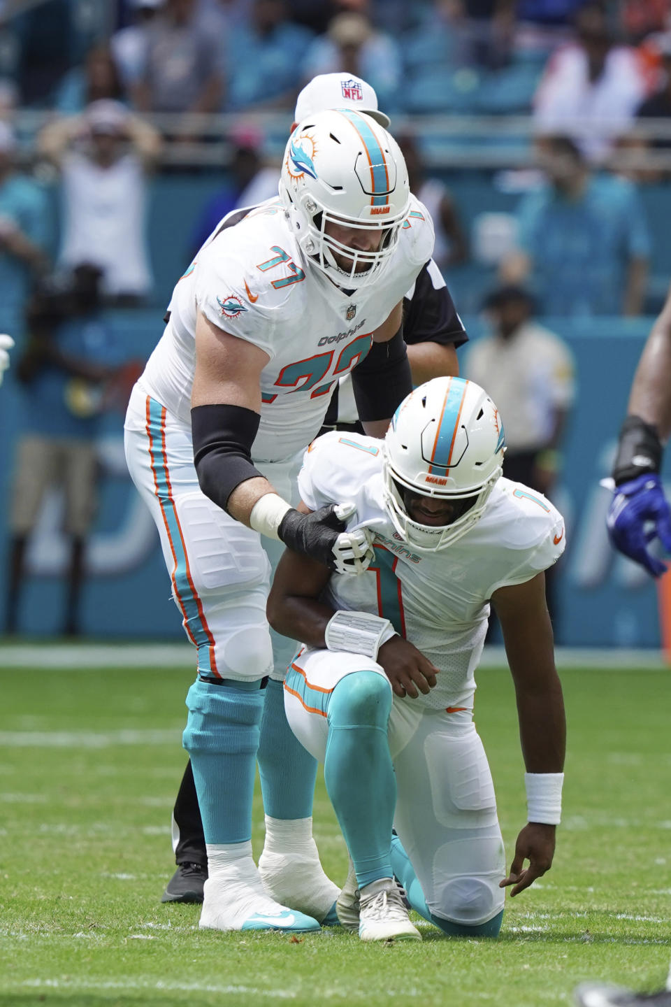 Miami Dolphins quarterback Tua Tagovailoa (1) is assisted by offensive guard Jesse Davis (77), during the first half of an NFL football game against the Buffalo Bills, Sunday, Sept. 19, 2021, in Miami Gardens, Fla. (AP Photo/Hans Deryk)