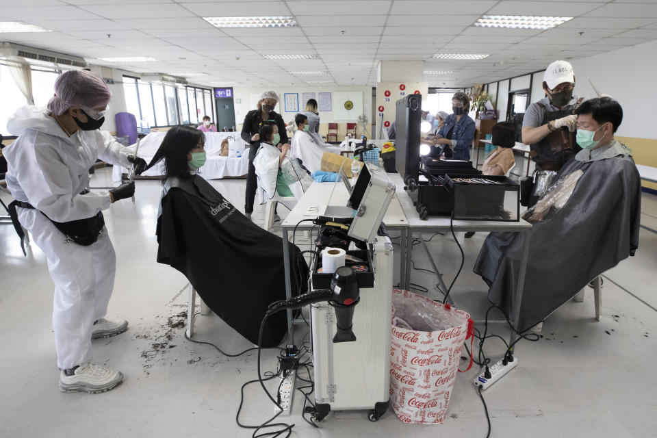 In this Tuesday, April 28, 2020, photo, Pornsupa Hattayong, left, and volunteers of hairdressers give haircuts to medical workers treating COVID-19 patients at Bangkok Metropolitan Administration General Hospital in Bangkok, Thailand. Pornsupa, a 43-year-old hairstylist, is boosting the morale of frontline medical workers by dispensing free haircuts at Bangkok hospitals since Thailand’s hair salons have been closed for more than a month, to help stop the spread of the coronavirus. (AP Photo/Sakchai Lalit)