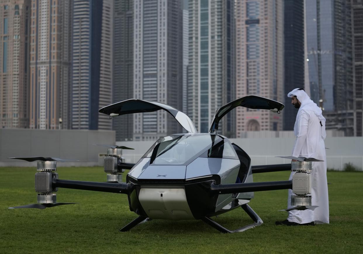 A man looks at the XPeng X2, an electric flying taxi developed by the Guangzhou-based XPeng, Inc's aviation affiliate, being tested in front of the Marina District in Dubai, United Arab Emirates, Monday, Oct. 10, 2022. Monday’s demonstration was held with an empty cockpit, but the company says it carried out a manned flight test last year of the two-passenger vehicle. (AP Photo/Kamran Jebreili)