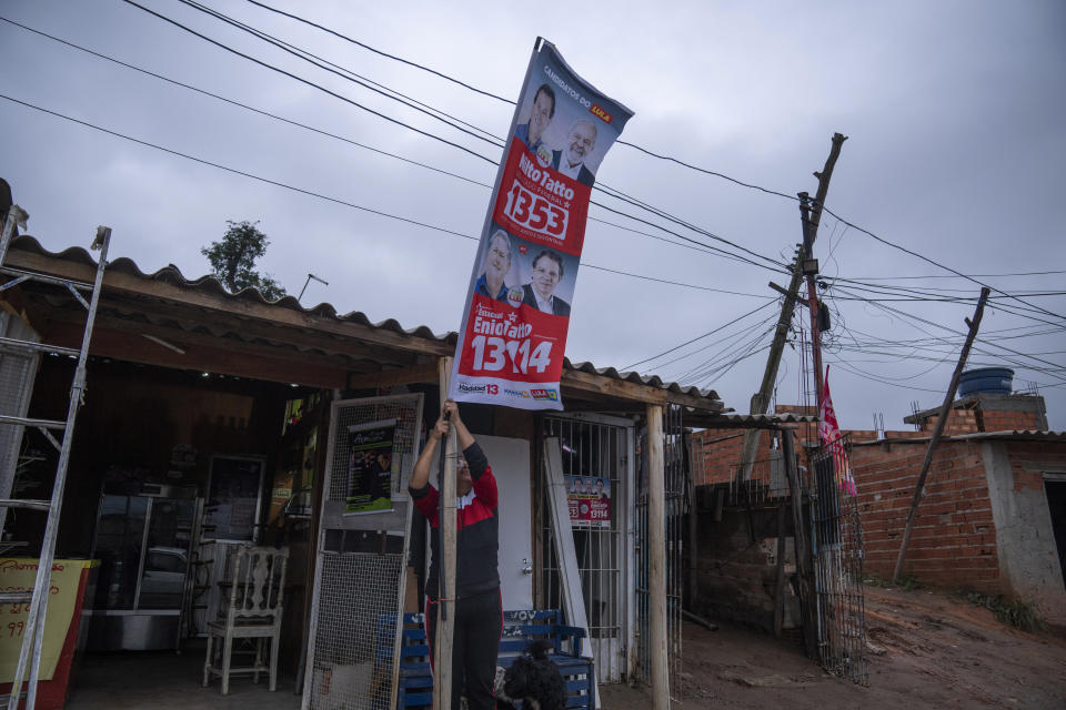 Una mujer coloca un cartel promoviendo candidatos al Congreso por el Partido de los Trabajadores de Lula, el favorito en la segunda vuelta del 30 de octubre. Foto del 29 de septiembre del 2022. (AP Photo/Victor R. Caivano, File)