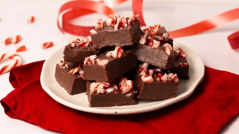 Peppermint fudge pieces garnished with candy cane pieces on a plate