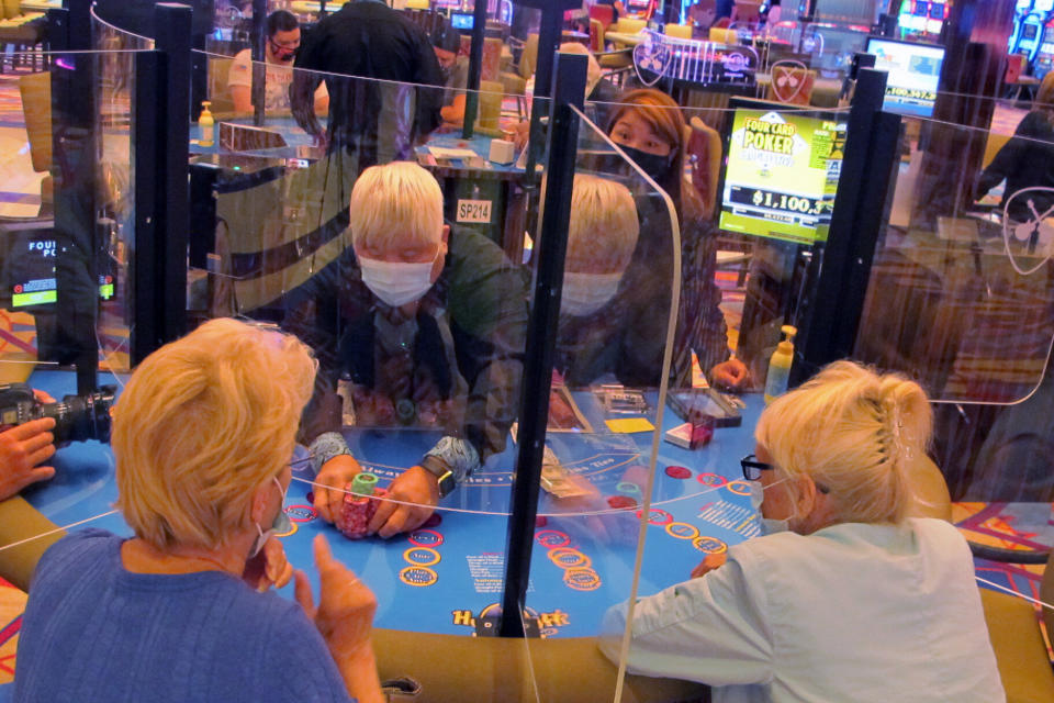 See-through barriers separate gamblers and a dealer at a card table at the Hard Rock casino in Atlantic City, N.J., on July 2, 2020, the first day it reopened after being closed for four months due to the coronavirus outbreak. American Gaming Association President Bill Miller said Tuesday, Oct. 27, 2020, the industry is adapting to the pandemic but needs assistance from the government for its casinos and workers. (AP Photo/Wayne Parry)