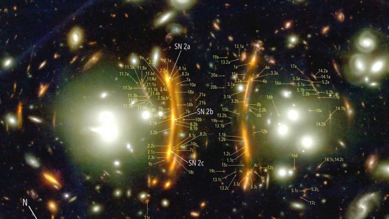  A JWST image of two large bright galaxies ringed in orange light from a distant supernova. 