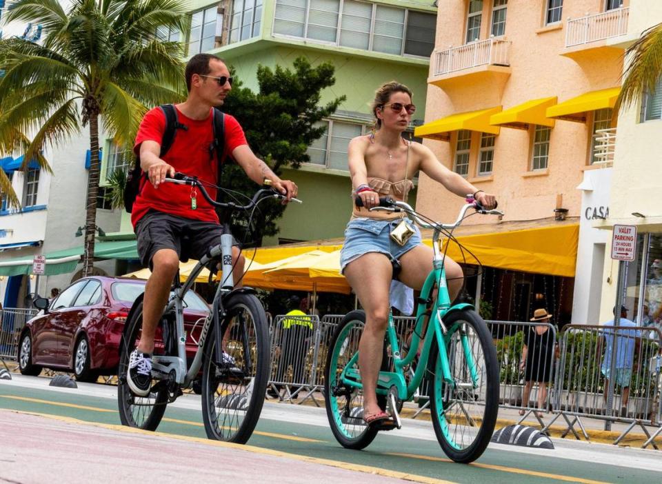 French tourists Clement and Juliette ride bikes up Ocean Drive during Memorial Day weekend at Miami Beach, Florida, on Monday, May 29, 2023.