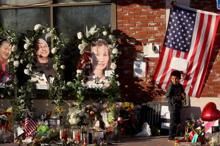 MONTEREY PARK, CA - JANUARY 26, 2023 - - Julien Espinoza, 5, from Alhambra, pays his respects at the memorial for 11 people who died in a mass shooting during Lunar New Year celebrations outside the Star Ballroom Dance Studio in Monterey Park on January 26, 2023. Espinoza visited the memorial with his mother Marissa Acosta. (Genaro Molina / Los Angeles Times)