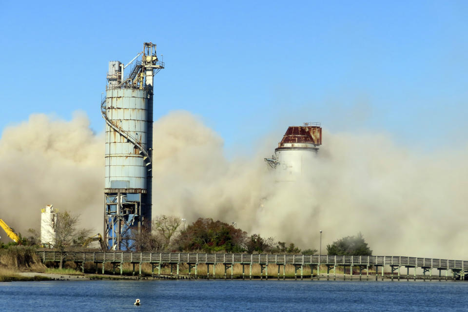 Debris and dust fill the air after smokestack at the former B.L. England power plant in Upper Township, N.J., was felled during a control demolition, Thursday, Oct. 26, 2023. The site will be redeveloped as a mixed use residential and commercial project, and a nearby electrical substation will be used to connect New Jersey's soon-to-come offshore wind farms with the electrical grid. (AP Photo/Wayne Parry)