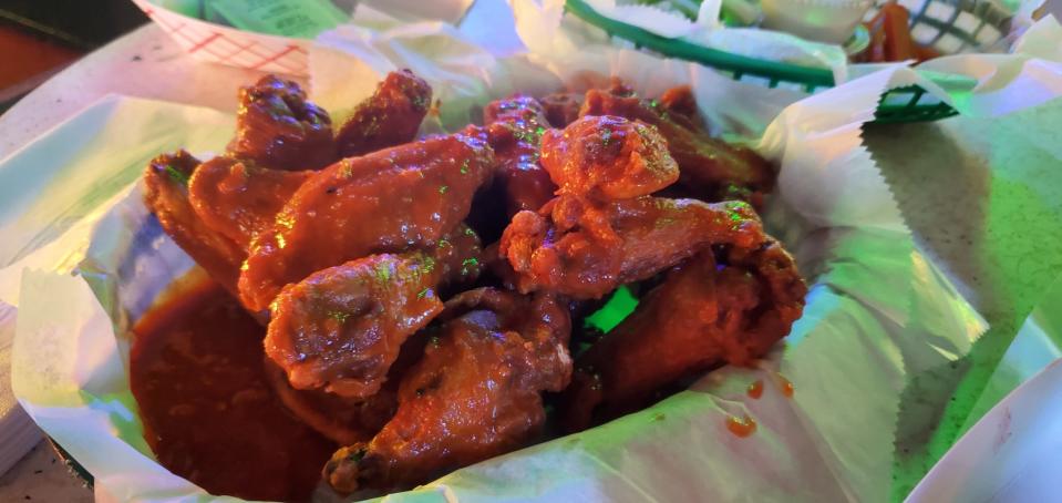 A green basket of buffalo wings bask in neon green light