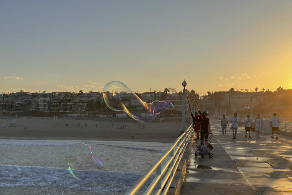 A man creates giant soap suds bubbles at dawn Monday, Sept. 5, on the Manhattan Beach Pier in Manhattan Beach, Calif., as a severe heat wave gripped the state. Most of California's 39 million people are facing sweltering weather. (AP Photo/John Antczak)