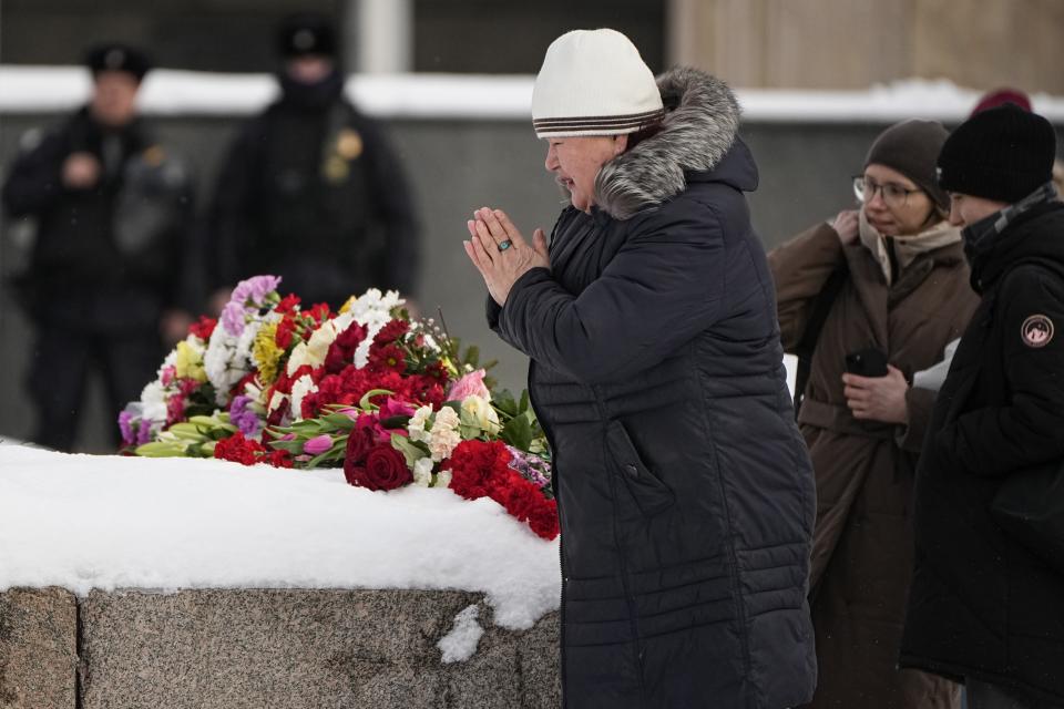 A woman reacts after laying flowers to pay the last respect to Alexei Navalny at the monument, a large boulder from the Solovetsky islands, where the first camp of the Gulag political prison system was established, near the historical the Federal Security Service (FSB, Soviet KGB successor) building in Moscow, Russia, on Sunday, Feb. 18, 2024. Russians across the vast country streamed to ad-hoc memorials with flowers and candles to pay tribute to Alexei Navalny, the most famous Russian opposition leader and the Kremlin's fiercest critic. Russian officials reported that Navalny, 47, died in prison on Friday. (AP Photo/Alexander Zemlianichenko)