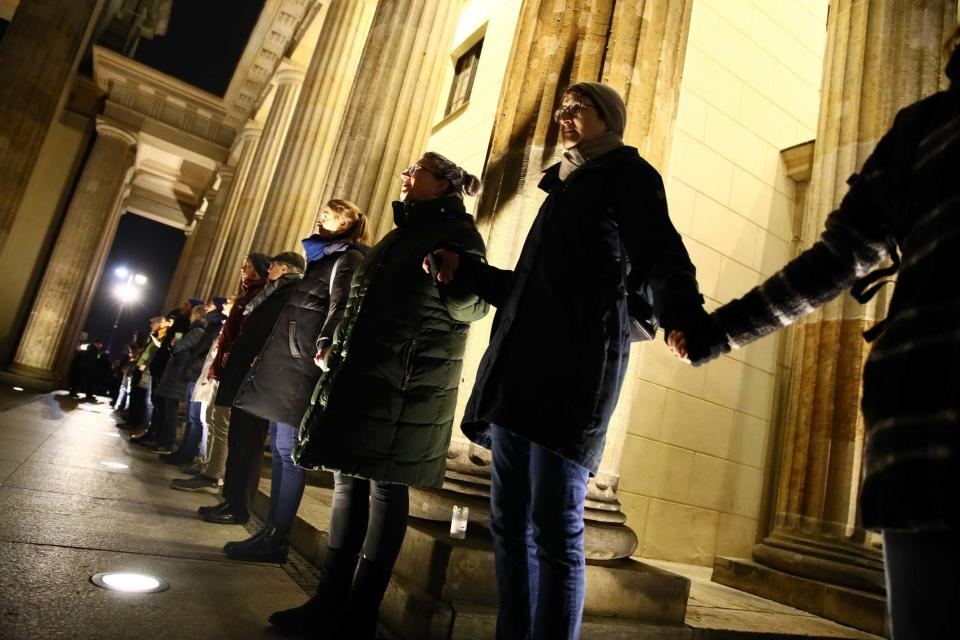 People gathered for a vigil at the Brandenburg Gate make a human chain in solidarity with victims (Getty Images)