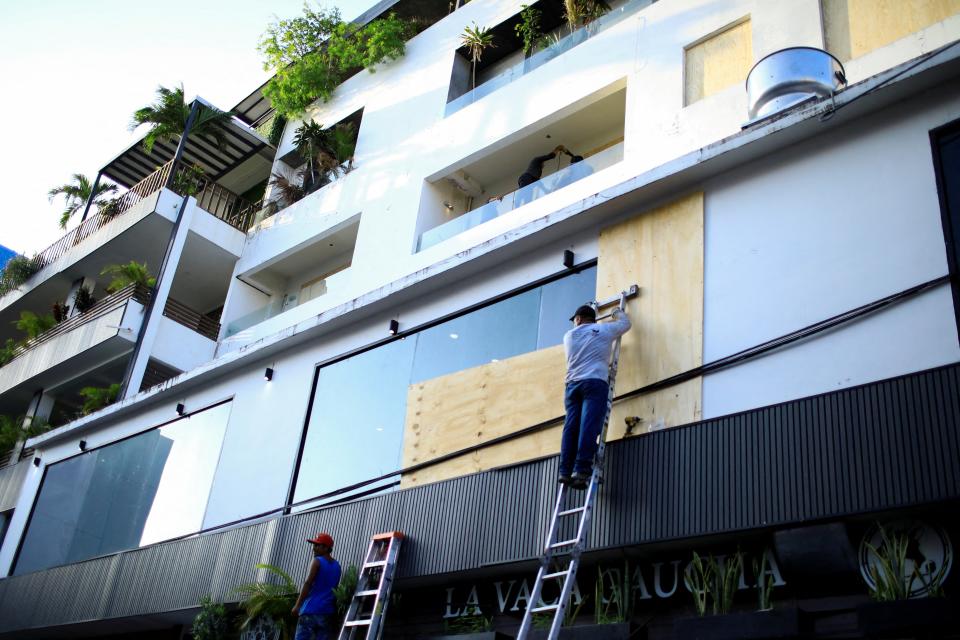 A worker installs wood boards on a building's windows ahead of Hurricane Beryl in Playa del Carmen, Mexico on July 3 (REUTERS)