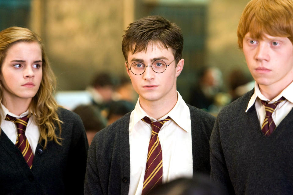 Radcliffe stands next to his costars Emma Watson and Rupert Grint in their Hogwarts uniforms