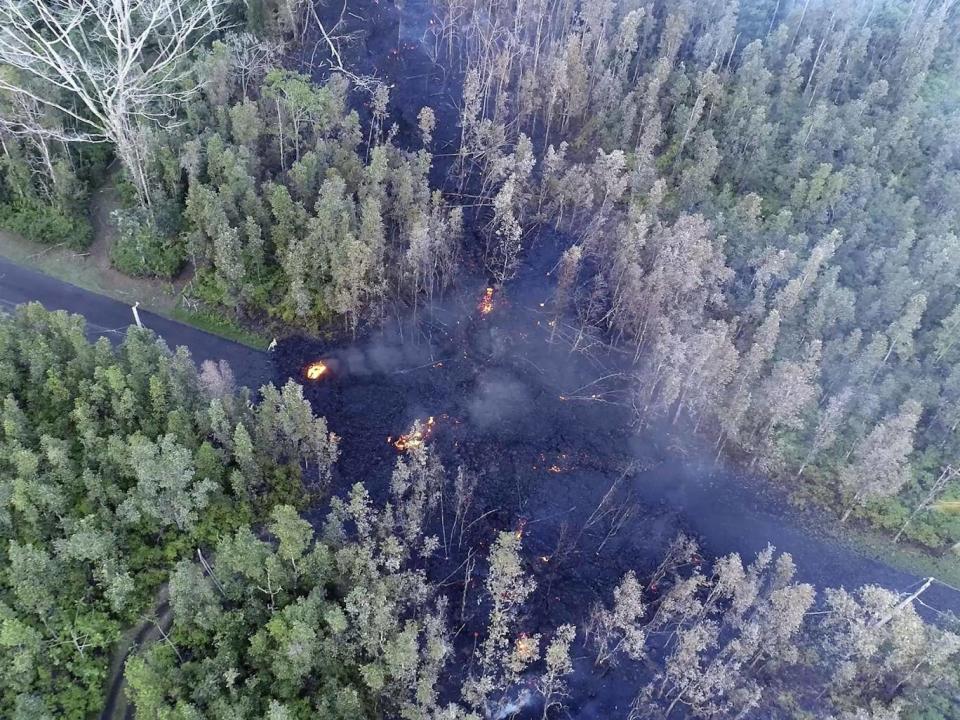 Lava flows over a road in the Puna District as a result of the eruption from Kilauea on Hawaii’s Big Island (Byron Matthews via AP)