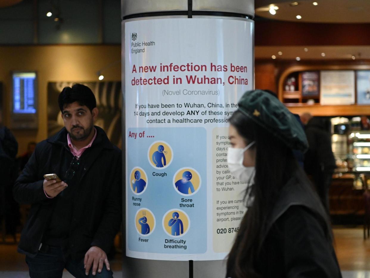 A woman wearing a face mask passes a Public Health England sign at London Heathrow Airport, the busiest airport in Europe, on 28 January 2020: Daniel Leal-OlivasAFP via Getty Images