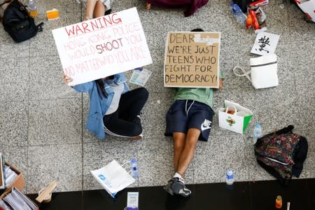 Anti-government demonstrators sit in a designated area of the arrival hall of the airport in Hong Kong after police and protesters clashed the previous night