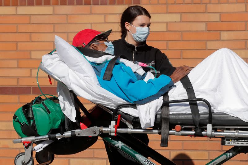 Healthcare worker wheels patient on stretcher into Wyckoff Heights Medical Center during outbreak of coronavirus disease (COVID-19) in New York