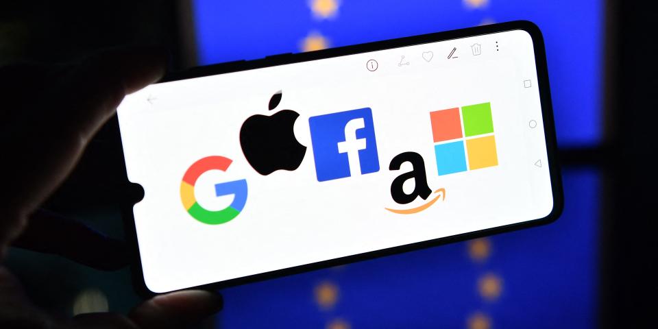 An illustration picture taken in London on December 18, 2020 shows the logos of Google, Apple, Facebook, Amazon and Microsoft displayed on a mobile phone with an EU flag displayed in the background.